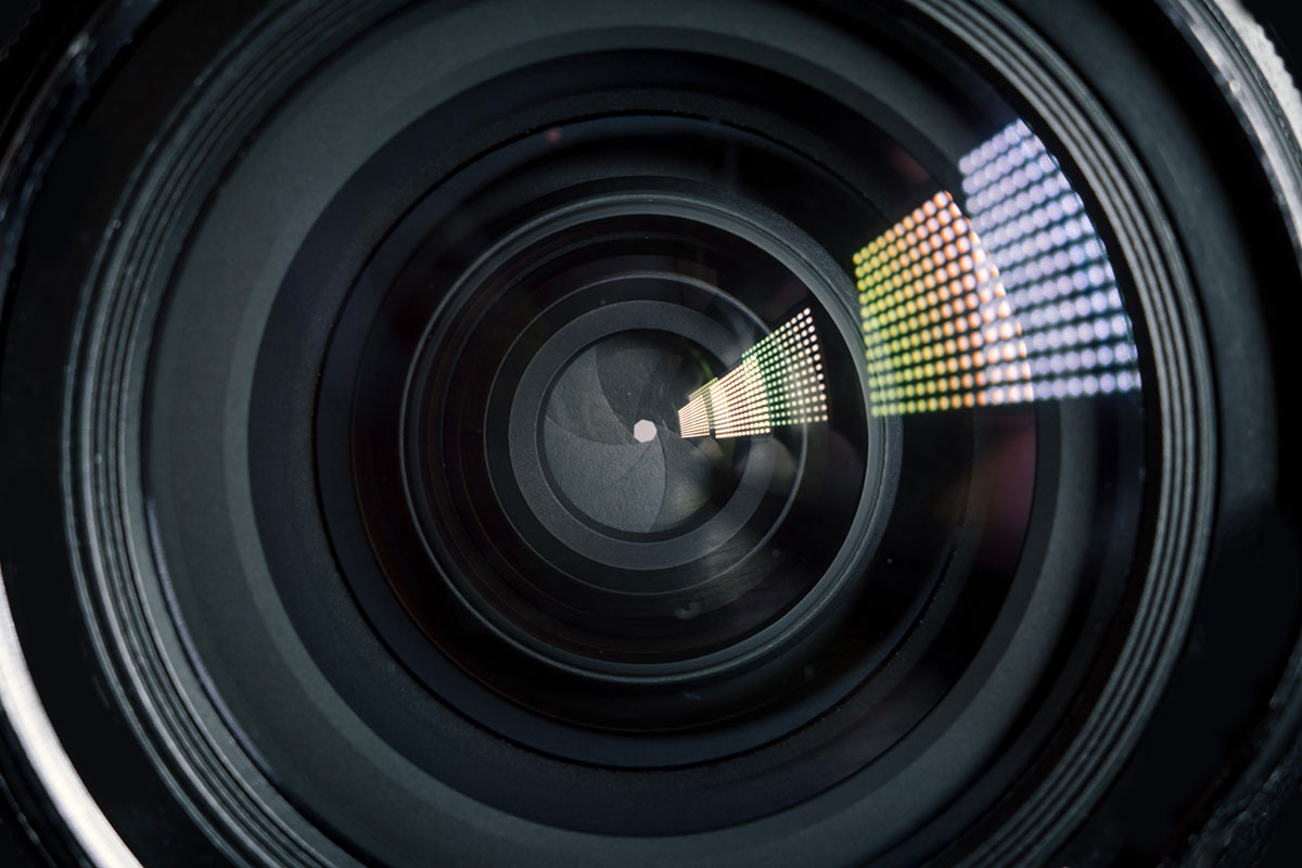 Close up of a camera lens, with a closed aperture and light reflecting off the glass